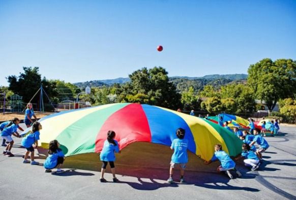 Large group of campers playing with a parachute and ball at Summer @ Stratford summer camp in L.A.