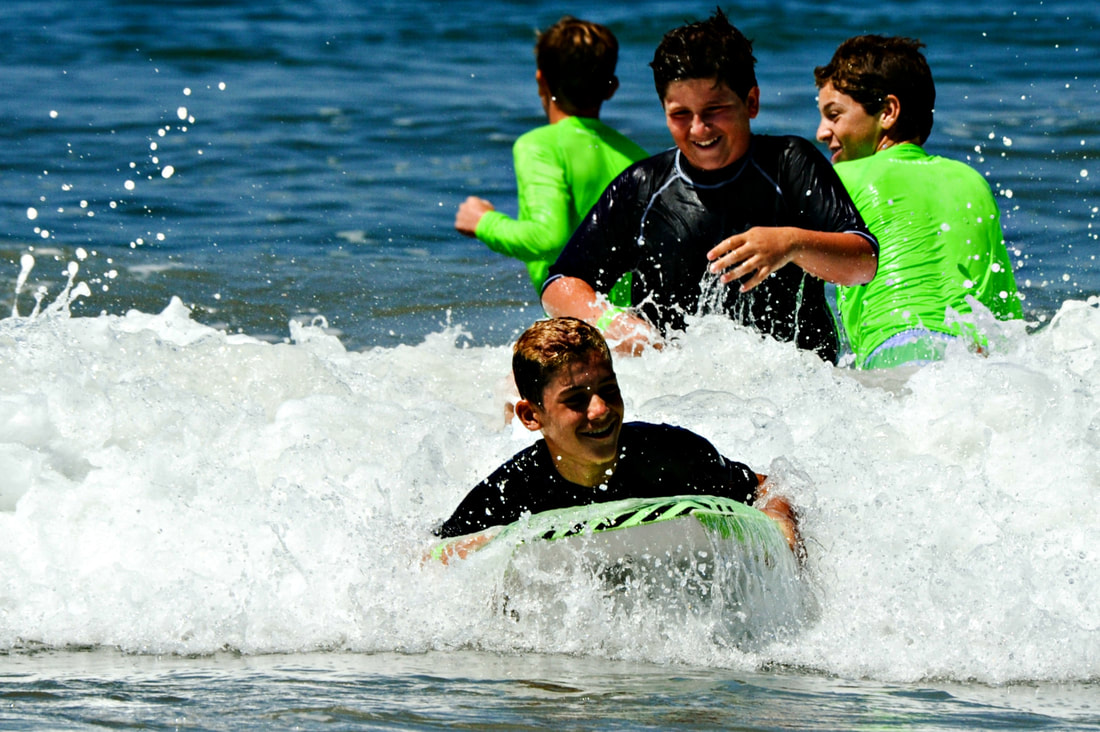 4 teenage boys from Costa Mesa swimming, boogie boarding and having fun in the ocean at camp.