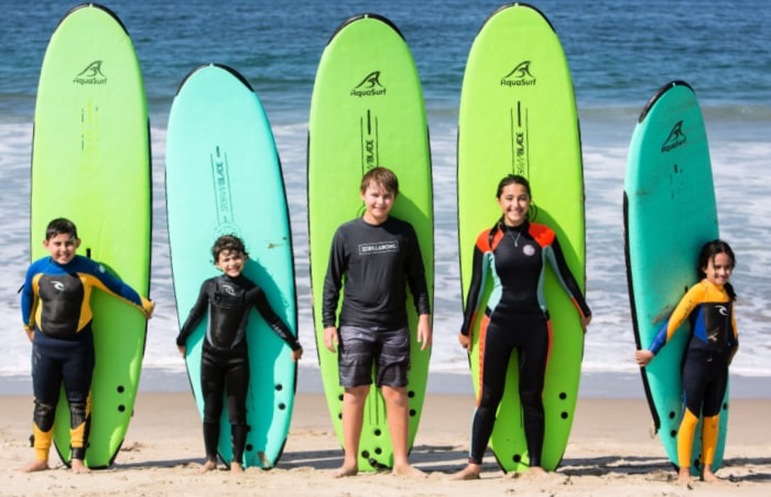 5 campers with surfboards standing on the beach at Aqua Surf Camp in Santa Monica