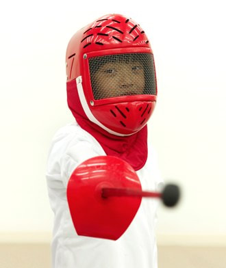 Child holding a sword and wearing protective fencing gear at Avant Garde Fencing Summer Camp in Los Angeles.
