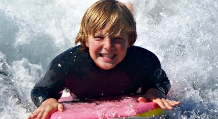 Boy boogie boarding at summer beach camp in Los Angeles
