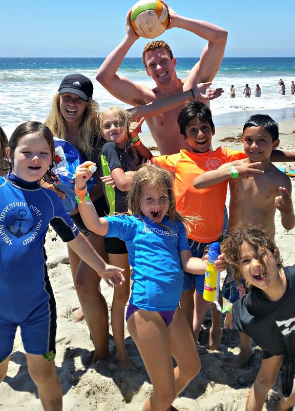 Five kids and two camp counselors playing together on the beach at summer camp in Los Angeles
