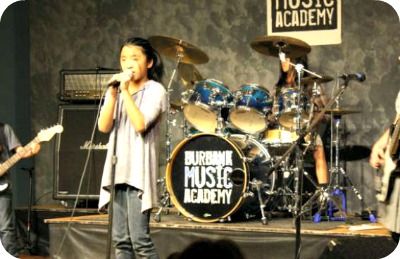 Girl signing into a microphone with her bank at Burbank Music Academy Summer Camp