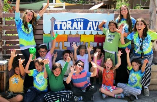 Three famale camp counselors and 10 campers in their summer camp group making funny faces and posing for the camera at Camp Gan Izzy Jewish Summer Camp in the Pacific Palisades.