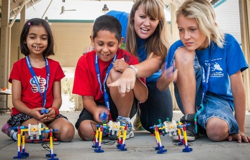 Three campers and their camp counselor at Destination Science summer camp doing a robotics activity together