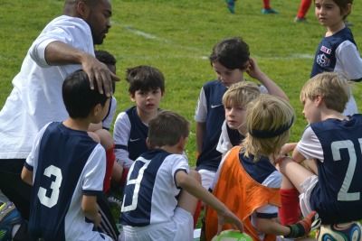 Soccer campers huddling with their coach on the sideline at Hollywood Soccer Academy Summer Camp in Los Angeles.