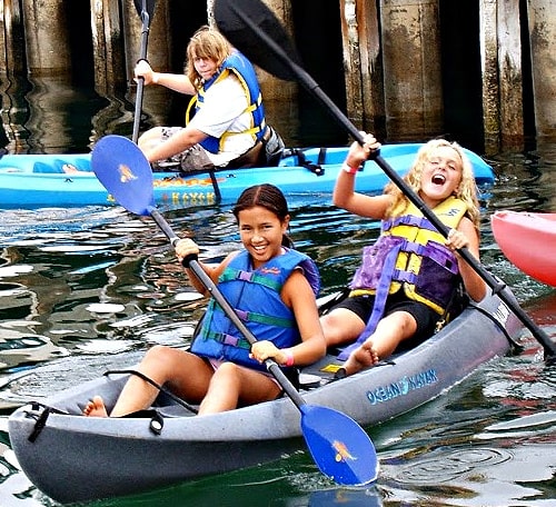 Three girls ocean kayaking at summer camp in Los Angeles