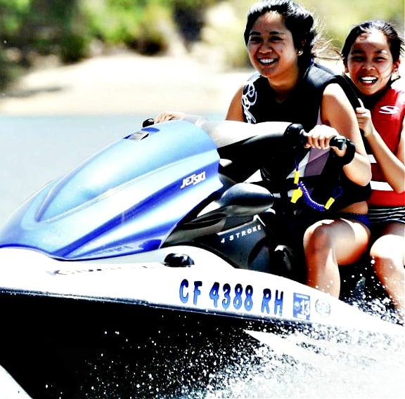 Female camp counselor and camper jet skiing together at summer camp