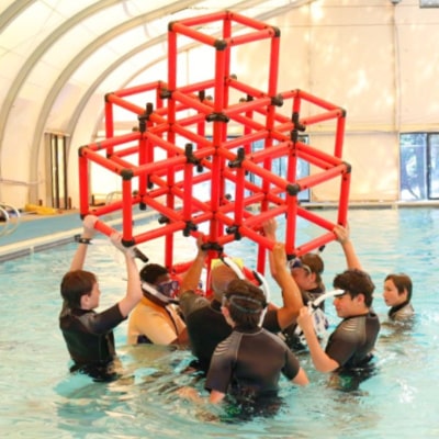 Group of campers in a swimming pool making a cube from pvc plastic at AstroCamp