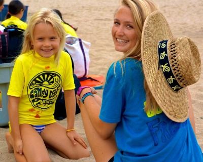 Camper and her camp counselor sitting together on the beach at Sandy Days Kids Camp in the Pacific Palisades.