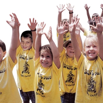 Six Sports Plus Day Camp boys wearing camp t-shirts with their arms up in the air.