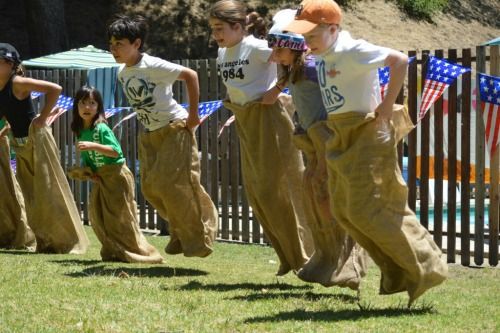 Five boys and girls participating in potato sack races at Tumbleweed Day Camp.