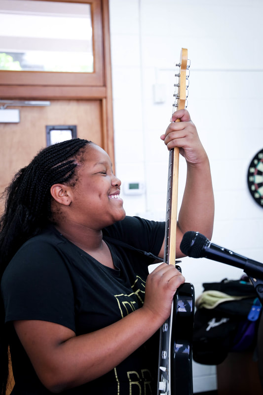 Female camper playing bass guitar at Amplify Sleepaway Camp for Girls