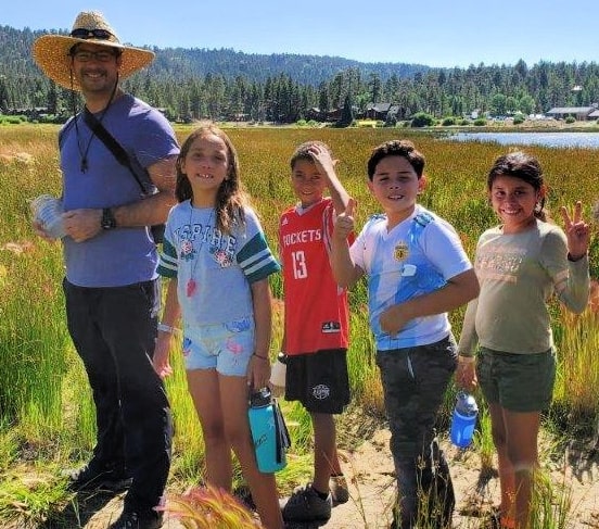 Four campers and their camp counselor enjoying a nature hike at summer camp